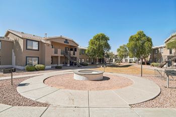 A courtyard with a circular concrete structure in the middle surrounded by houses.